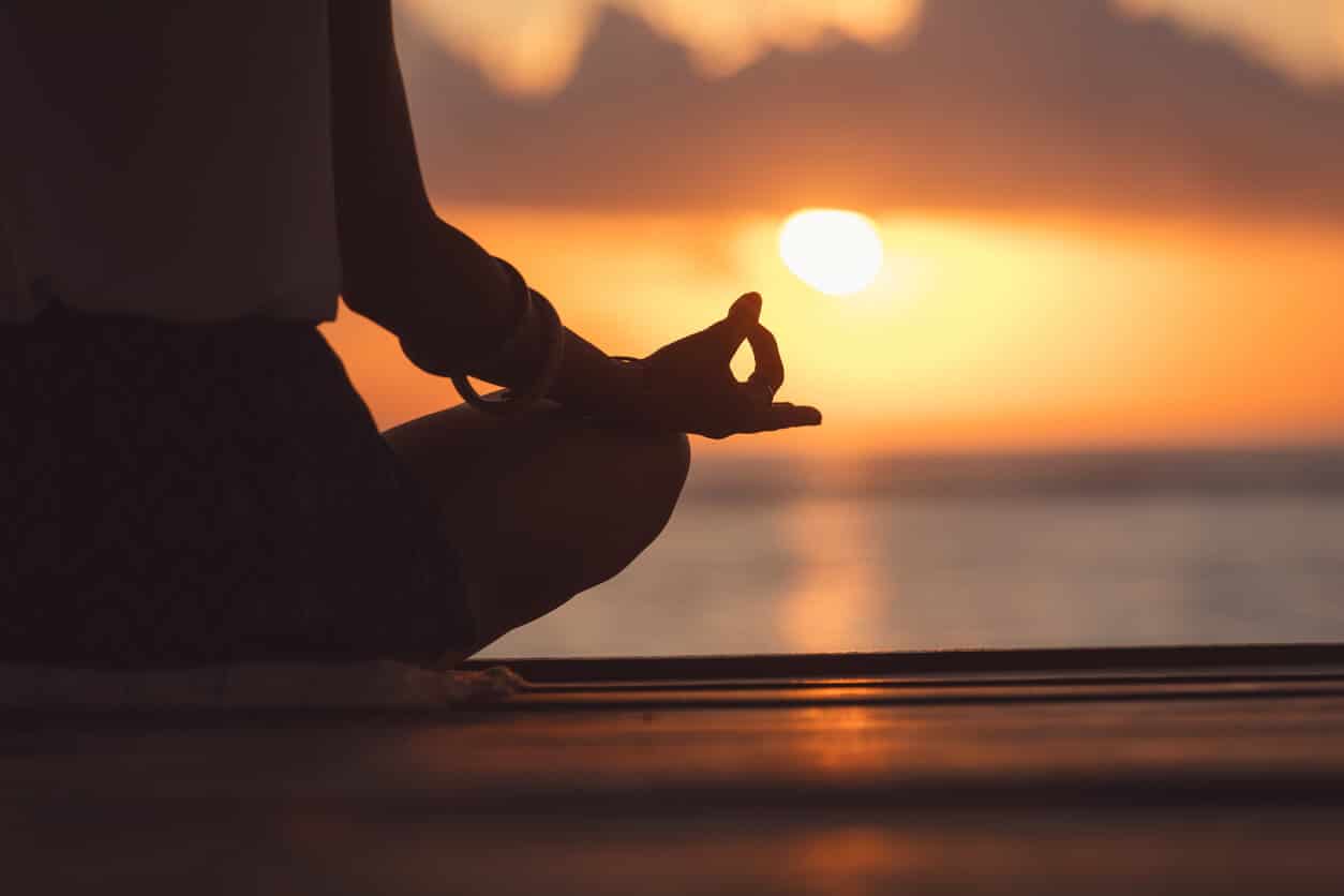 a silhoutte of a person doing yoga with the sun setting in the background