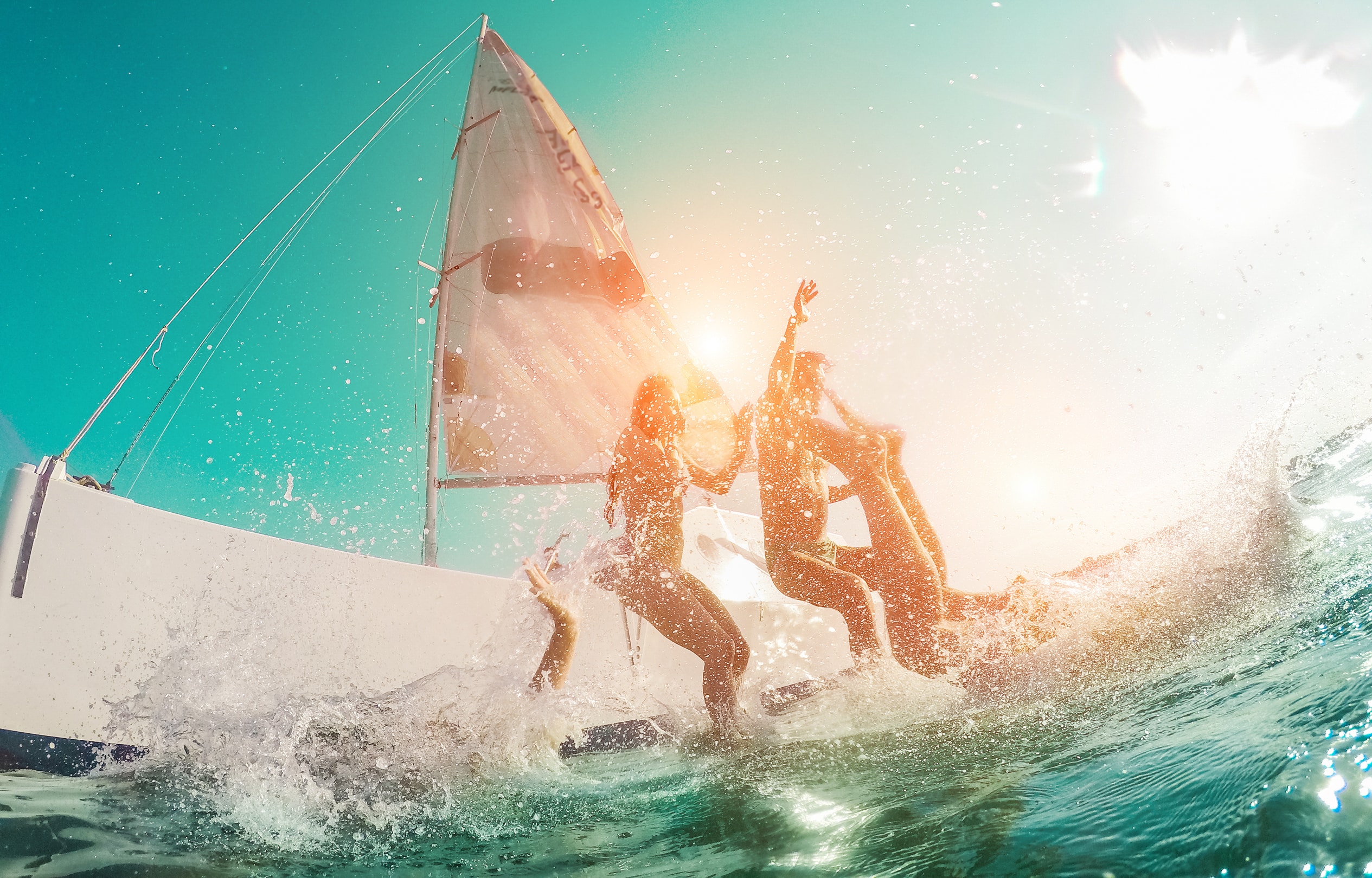 Friends Diving From Sailing Boat Into The Sea